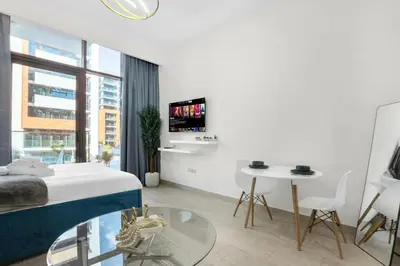 a white room with a bed and a table and a tv at Exclusive Downtown Dubai Studio in Dubai