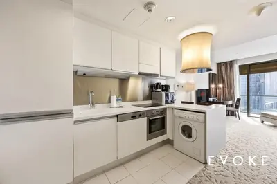 a kitchen with white cabinets and a dishwasher at Kempinski Luxe Studio Burj Khalifa View by Evoke in Dubai
