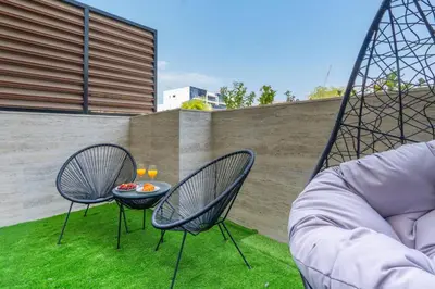 a patio with two chairs and a table on the grass at Luxury Apartment In JVC With Padel Gym Pool Cinema BBQ in Dubai
