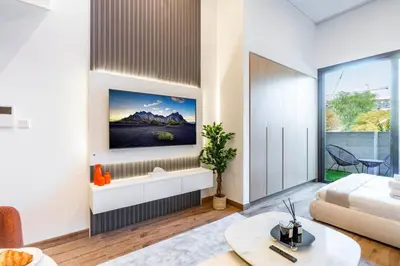 a living room with a bed and a large window at Luxury Apartment In JVC With Padel Gym Pool Cinema BBQ in Dubai