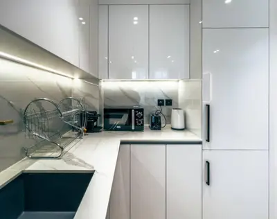 a kitchen with white cabinets and a microwave at Modern Place - Binghatti Azure 1244 in Dubai