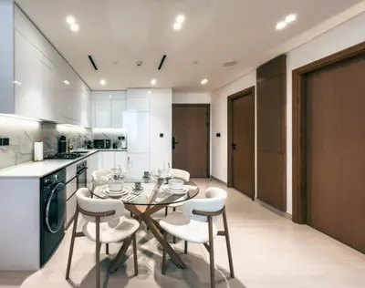 a kitchen with a dining table and white chairs at Modern Place - Binghatti Azure 1244 in Dubai