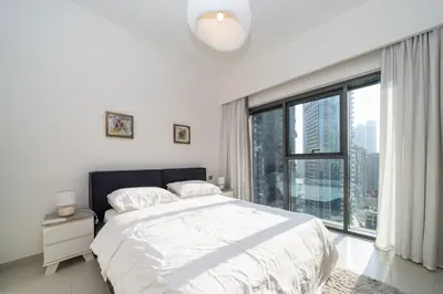 a white bedroom with a bed and a large window at Burj Royale Luxury Burj Khalifa dubai mall downtown city centre in Dubai
