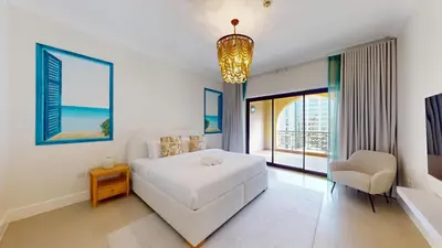 a bedroom with a white bed and a chair at Golden Mile - Serene Two Bedroom on the Palm in Dubai