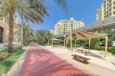 a park with a bench and palm trees and buildings at Golden Mile - Serene Two Bedroom on the Palm in Dubai