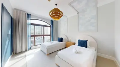 a white bedroom with two beds and a window at Golden Mile - Serene Two Bedroom on the Palm in Dubai