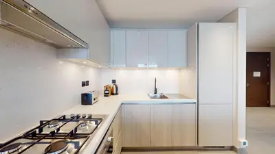 a kitchen with white cabinets and a stove and a sink at The Crest A - Premium Two Bedroom High-Rise Escape in Dubai
