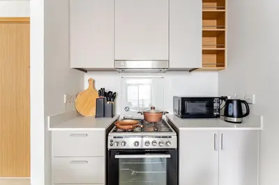 a white kitchen with a stove and a microwave at Creek crescent high floor in Dubai