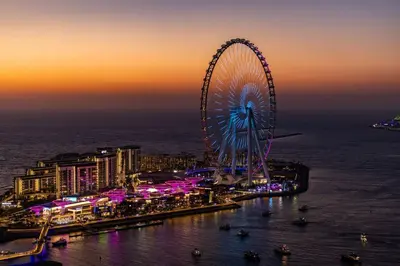 a large ferris wheel in a city at night at Jbr shams apartment in Dubai