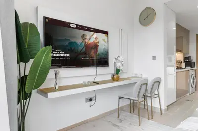 a living room with a tv on a wall at Studio in Azizi with Pool and Gym Access in Dubai