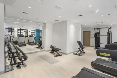 a gym with treadmills and chairs in a room at Studio in Azizi with Pool and Gym Access in Dubai
