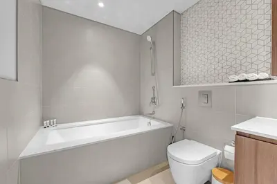a bathroom with a tub and a toilet and a sink at Guest Favorite - Premium & Modern 2BR Stay at Dubai Creek Harbour in Dubai