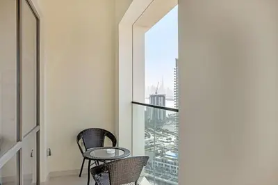 a balcony with two chairs and a glass table at Guest Favorite - Premium & Modern 2BR Stay at Dubai Creek Harbour in Dubai
