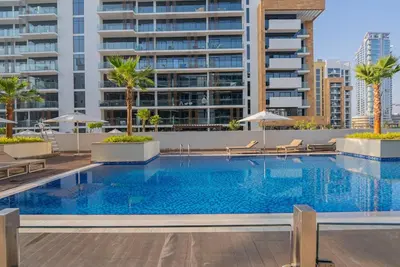 a swimming pool with chairs and a building at Chic Urban Studio in Dubai in Dubai