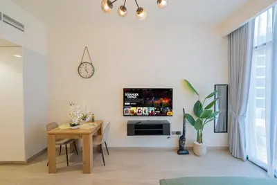 a living room with a table and a tv on a wall at Chic Urban Studio in Dubai in Dubai