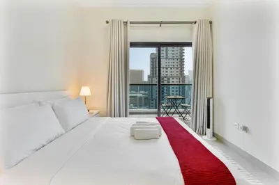 a bedroom with a large white bed with a red rug at Chic 1BR with City Views Near Marina & Metro in Dubai