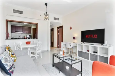a living room with a couch and a tv and a table at Chic 1BR with City Views Near Marina & Metro in Dubai