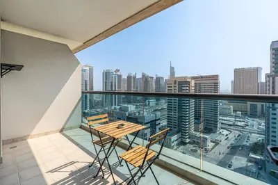 a balcony with a table and chairs on top of a building at Chic 1BR with City Views Near Marina & Metro in Dubai