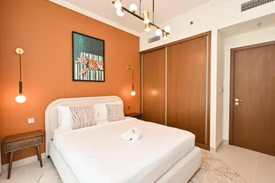 a bedroom with a white bed and an orange wall at Beach Serenity, Modern 1BR in Dubai, Palace Beach Residences, Emaar Beachfront in Dubai