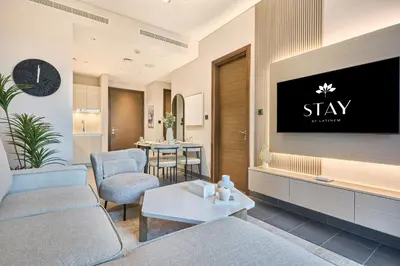 a living room with a tv on a wall at STAY BY LATINEM Luxury 1BR Holiday Home CB 0905 Near Burj Khalifa in Dubai