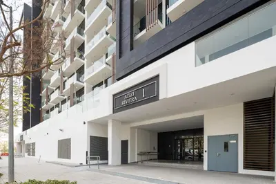 an external view of a white building with a black facade at Stylish Studio Apartment in Azizi Riviera One in Dubai
