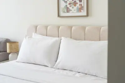 a white bed with white pillows in a bedroom at Stylish Studio Apartment in Azizi Riviera One in Dubai