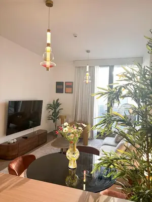 a living room with a vase of flowers on a table at Gym Spa Padel & E-scooter Designer Brand New 2BR in Dubai