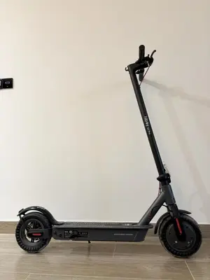 a black scooter parked against a white wall at Gym Spa Padel & E-scooter Designer Brand New 2BR in Dubai