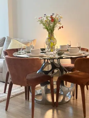 a dining room table with a vase of flowers on it at Gym Spa Padel & E-scooter Designer Brand New 2BR in Dubai