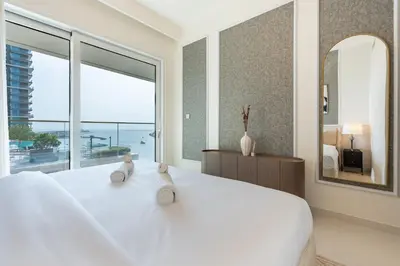 a white bedroom with a large bed and a large window at Chic 2 bedroom w Sunset and Palm Jumeirah Views in Dubai