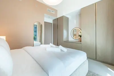 a bedroom with a large white bed with a mirror at Chic 2 bedroom w Sunset and Palm Jumeirah Views in Dubai