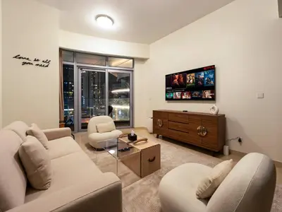 a living room with a couch and chairs and a tv at Downtown Charm Burj View 1BR in Dubai