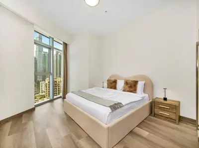 a white bedroom with a bed and a large window at Downtown Charm Burj View 1BR in Dubai