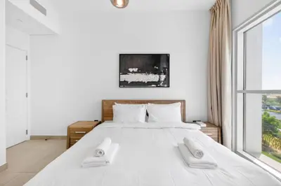a bedroom with a white bed with two towels on it at Dubai Hills 2BR Collective Tower in Dubai