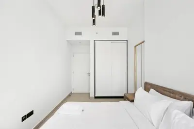 a white bedroom with a bed and a door at Dubai Hills 2BR Collective Tower in Dubai