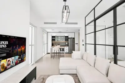 a living room with a white couch and a tv at Dubai Hills 2BR Collective Tower in Dubai