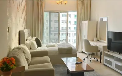 a living room with a couch and a bed and a television at Marine View Tower aparthotel in Dubai