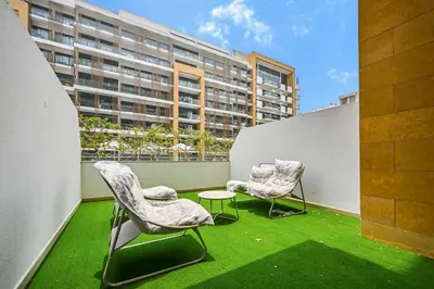 two chairs and a table on a balcony with a building at Modern Studio, Swimming Pool, Balcony, and Close to Burj Khalifa in Dubai