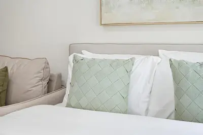 a bed with white sheets and pillows on it at Modern Studio, Swimming Pool, Balcony, and Close to Burj Khalifa in Dubai