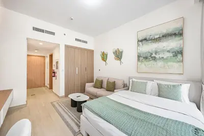 a white bedroom with a large bed and a couch at Modern Studio, Swimming Pool, Balcony, and Close to Burj Khalifa in Dubai