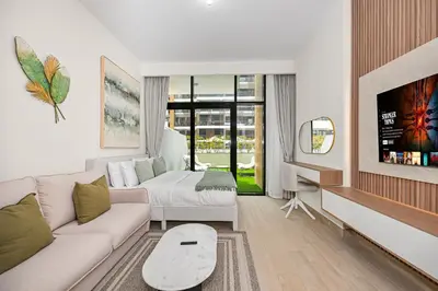 a living room with a couch and a tv at Modern Studio, Swimming Pool, Balcony, and Close to Burj Khalifa in Dubai