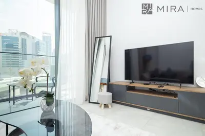 a living room with a tv and a glass table at Mira Holiday Homes - Paragon by IGO Studio Where Style Meets Comfort in Dubai