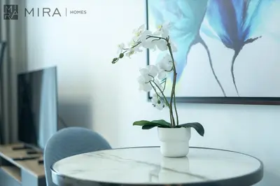 a vase with white flowers on a glass table at Mira Holiday Homes - Paragon by IGO Studio Where Style Meets Comfort in Dubai