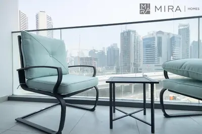 a chair and a table in front of a window at Mira Holiday Homes - Paragon by IGO Studio Where Style Meets Comfort in Dubai