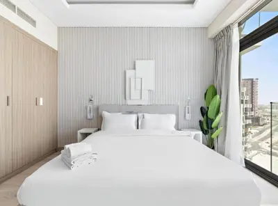 a white bedroom with a large white bed and a window at Elegant Apartment with Burj Khalifa View in Dubai