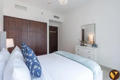 a bedroom with a white bed with blue pillows at Vogue Downtown Boulevard Central near Burj Khalifa and Dubai Mall, Two Bedroom Apartment with Balcony and Burj Khalifa View, Access to all Amenities in Dubai