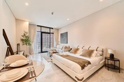 a living room with a large bed and a table at FAM Living Dubai Escape Sleek Studio at Peninsula Five in Dubai