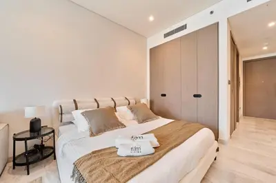a white bedroom with a large bed with towels on it at FAM Living Dubai Escape Sleek Studio at Peninsula Five in Dubai