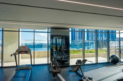 a gym with cardio equipment in a building with windows at 2-Bed Apartment with Infinity Pool in Dubai