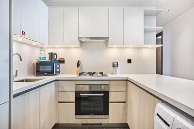 a kitchen with white cabinets and a stove top oven at STAY BY LATINEM Luxury 2BR Plus Study Holiday Home CB 3312 Near Burj Khalifa in Dubai